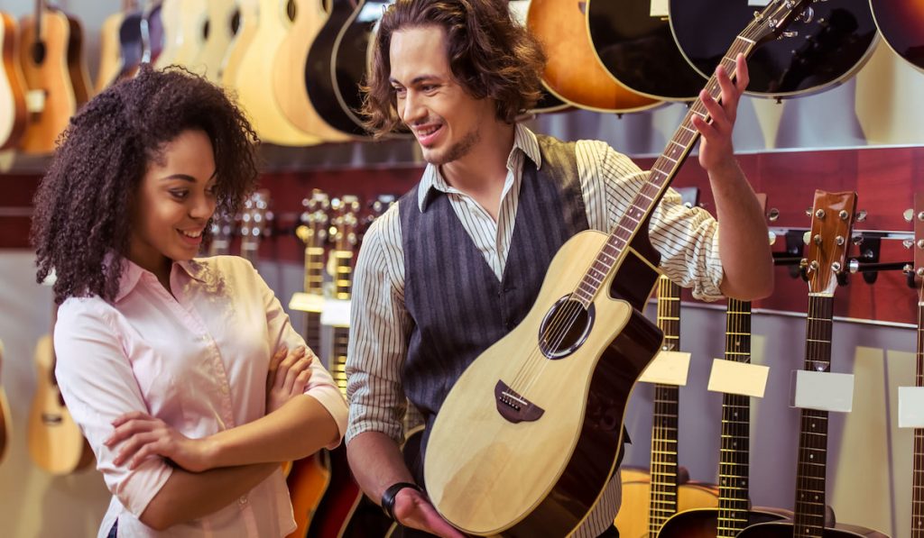 Woman and man choosing a guitar in a musical shop