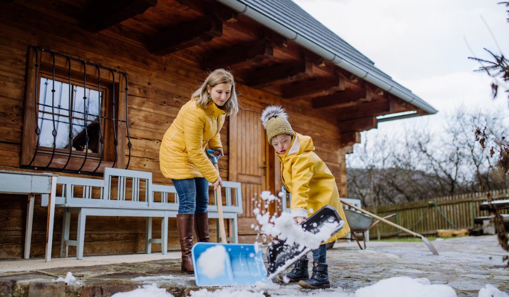 mother and son clearing snow from path in front of house 