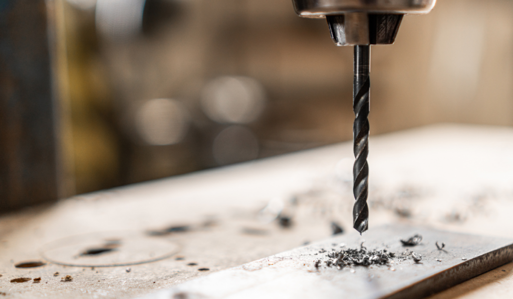 Drilling hole in steel plank in workshop
