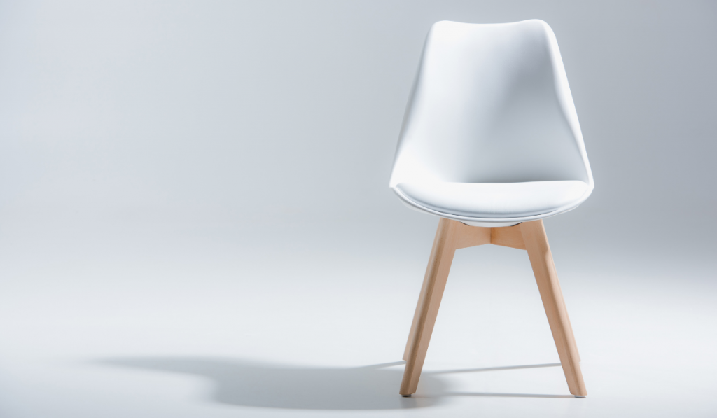 Studio shot of stylish chair with white top and light wooden legs standing on white