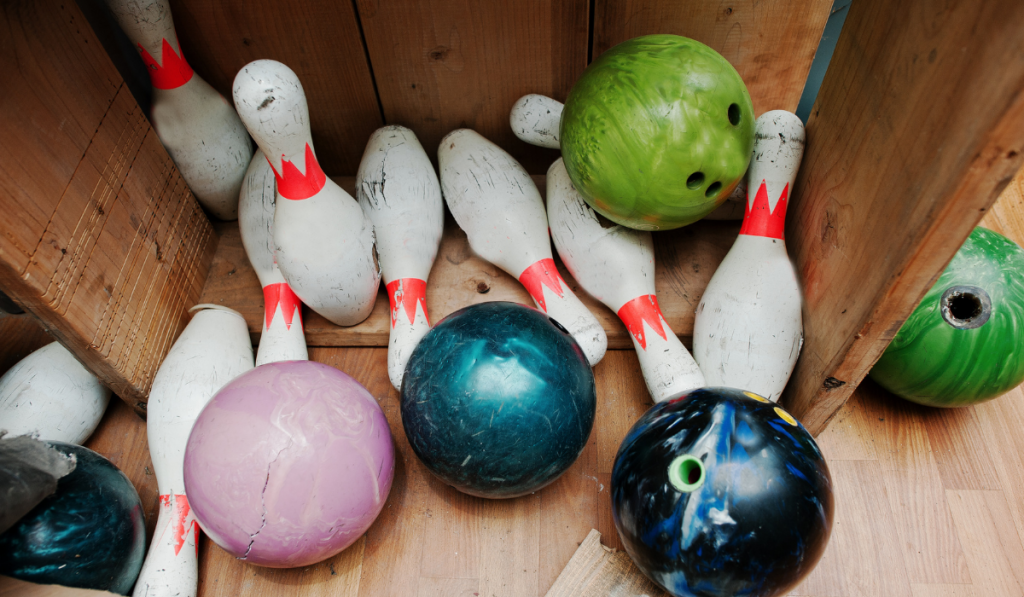 Crashed and damage bowling balls with pins at box
