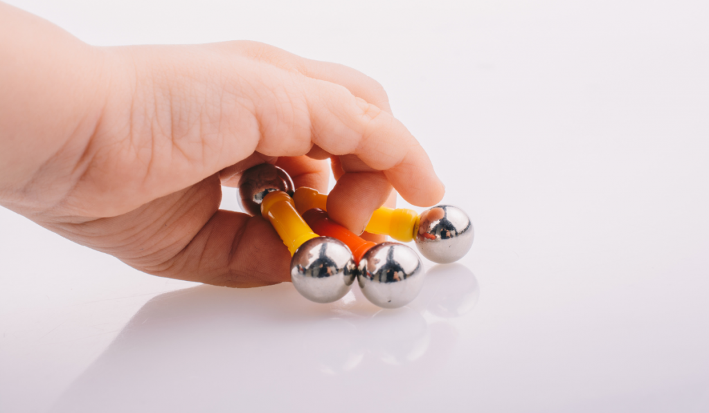 Hand holding magnet toy bars and magnetic balls on a white background
