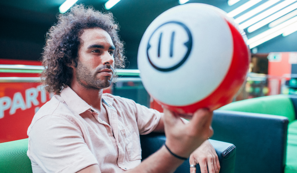 young man in casual outfit holding ball and looking away while spending time in bowling club