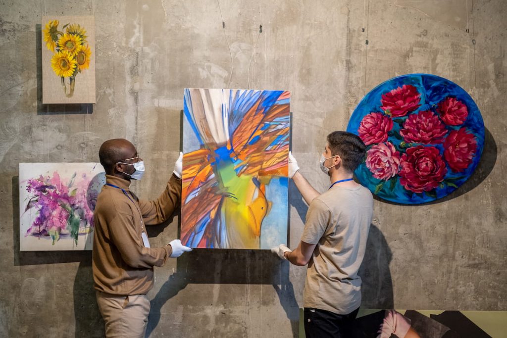 people hanging paintings for exhibition