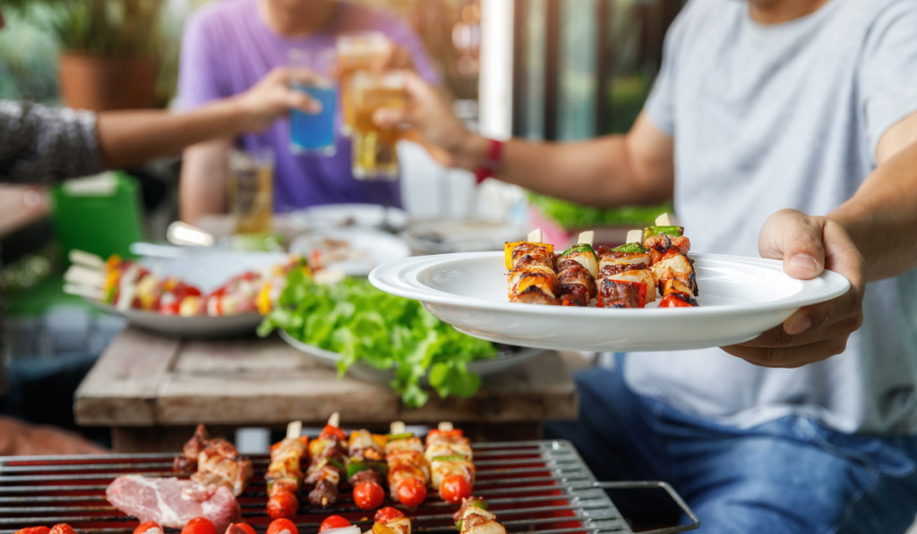 A man with a barbecue plate at a party between friends.