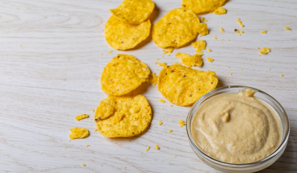 Close-up of crunchy chips with dip in bowl on table
