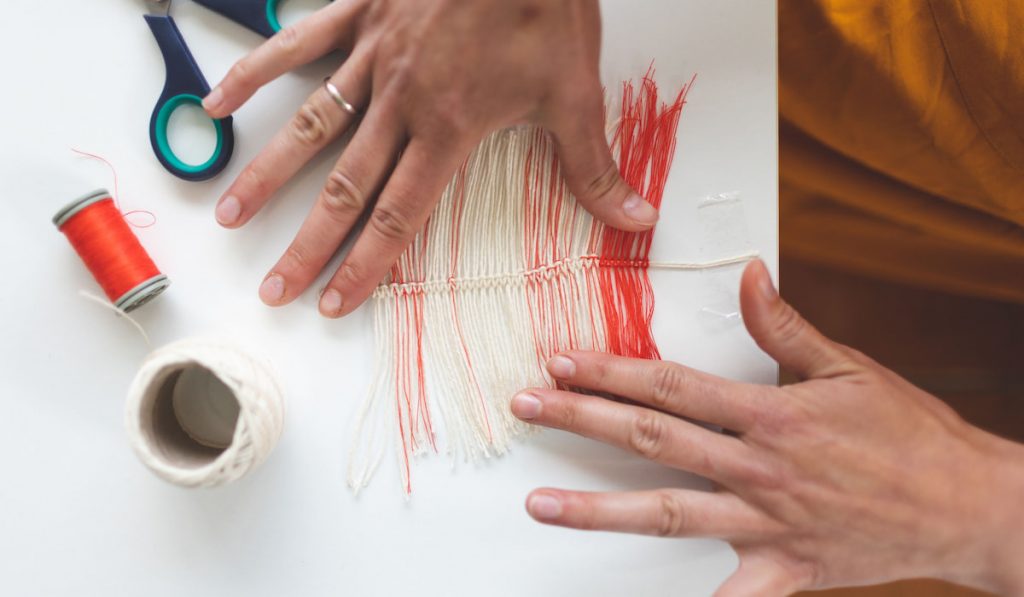 DIY Home Decor, Woman making a feather from thread, scissors and embroidery thread on the table