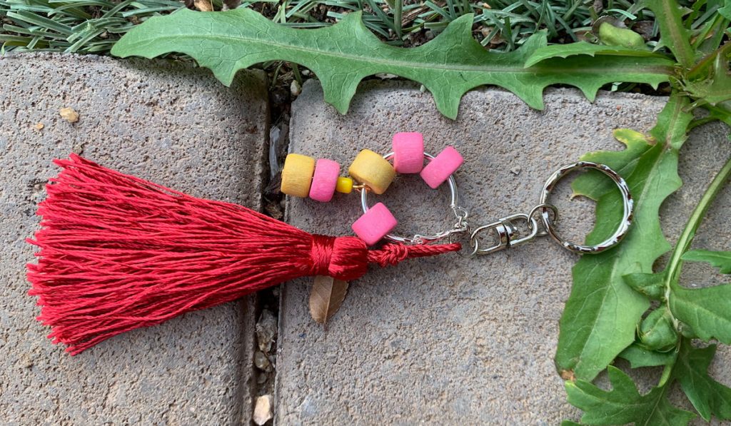 Handmade Embroidery thread tassel keychain on the ground near grass
